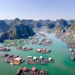 Aerial shot of Lan Ha Bay with floating fishing villages and lush cliffs in northern Vietnam.